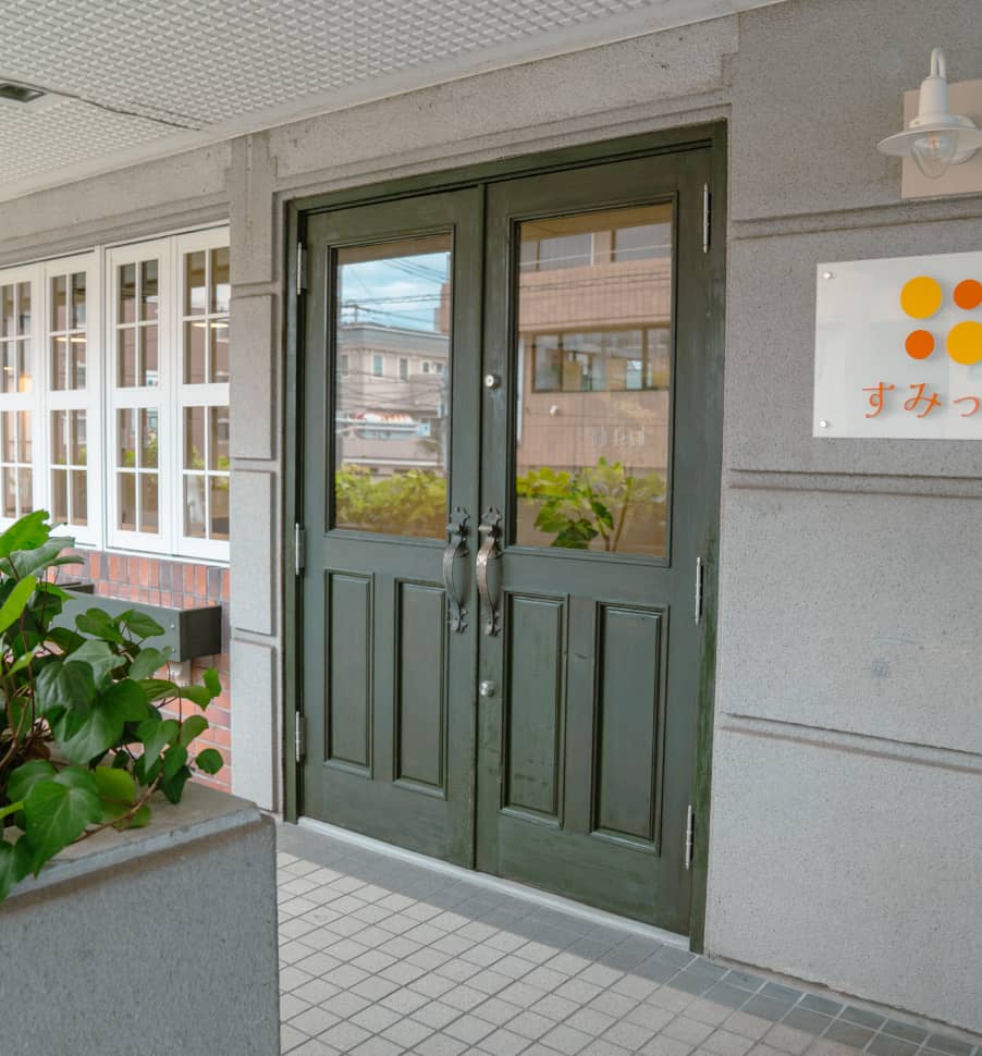 ダークグリーンの両開きドアとその周辺のエントランス