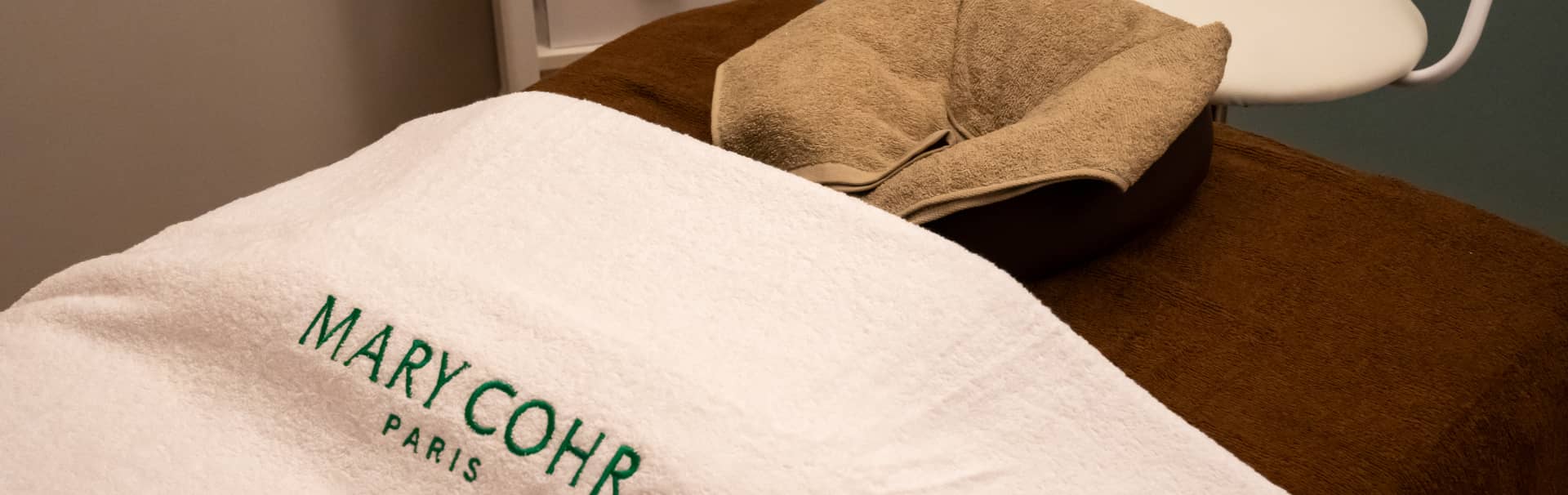 白いタオルに『MARY COHR PARIS』と刺繍されたスパの施術ベッド