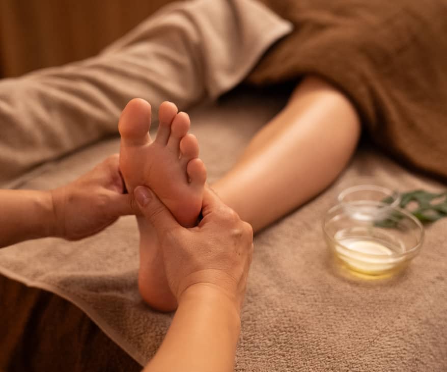温かみのある照明の下で行われるリフレクソロジーの施術風景