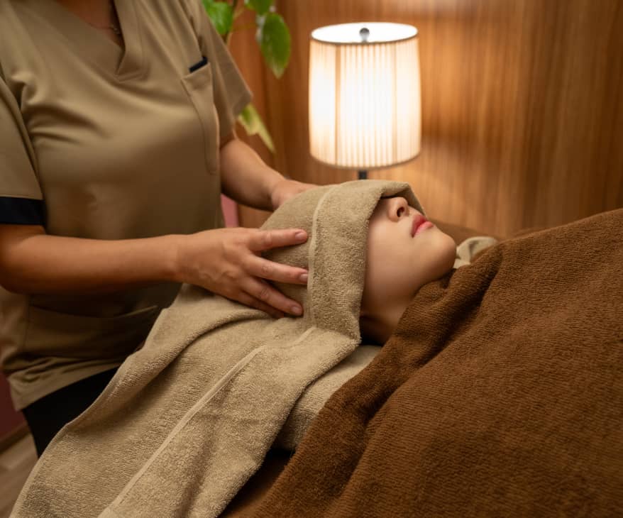 背景には柔らかい光を放つランプと観葉植物が見えるサロンの一角